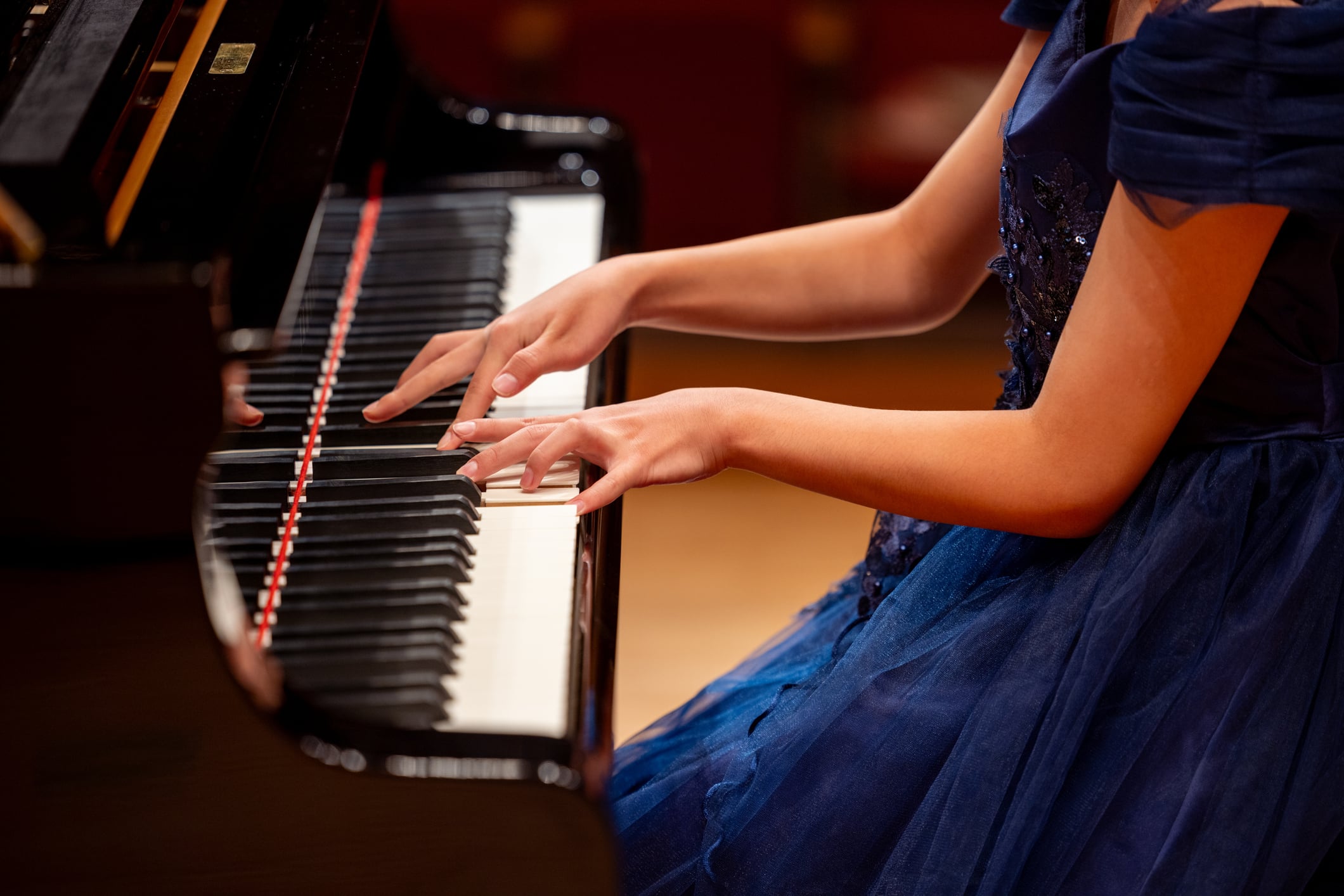 Person playing piano in blue dress.