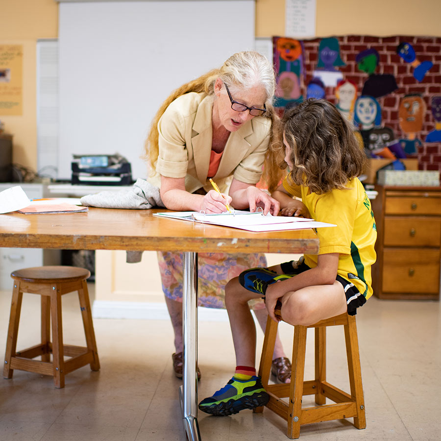 school-mid-row1 Teacher helping young student in classroom