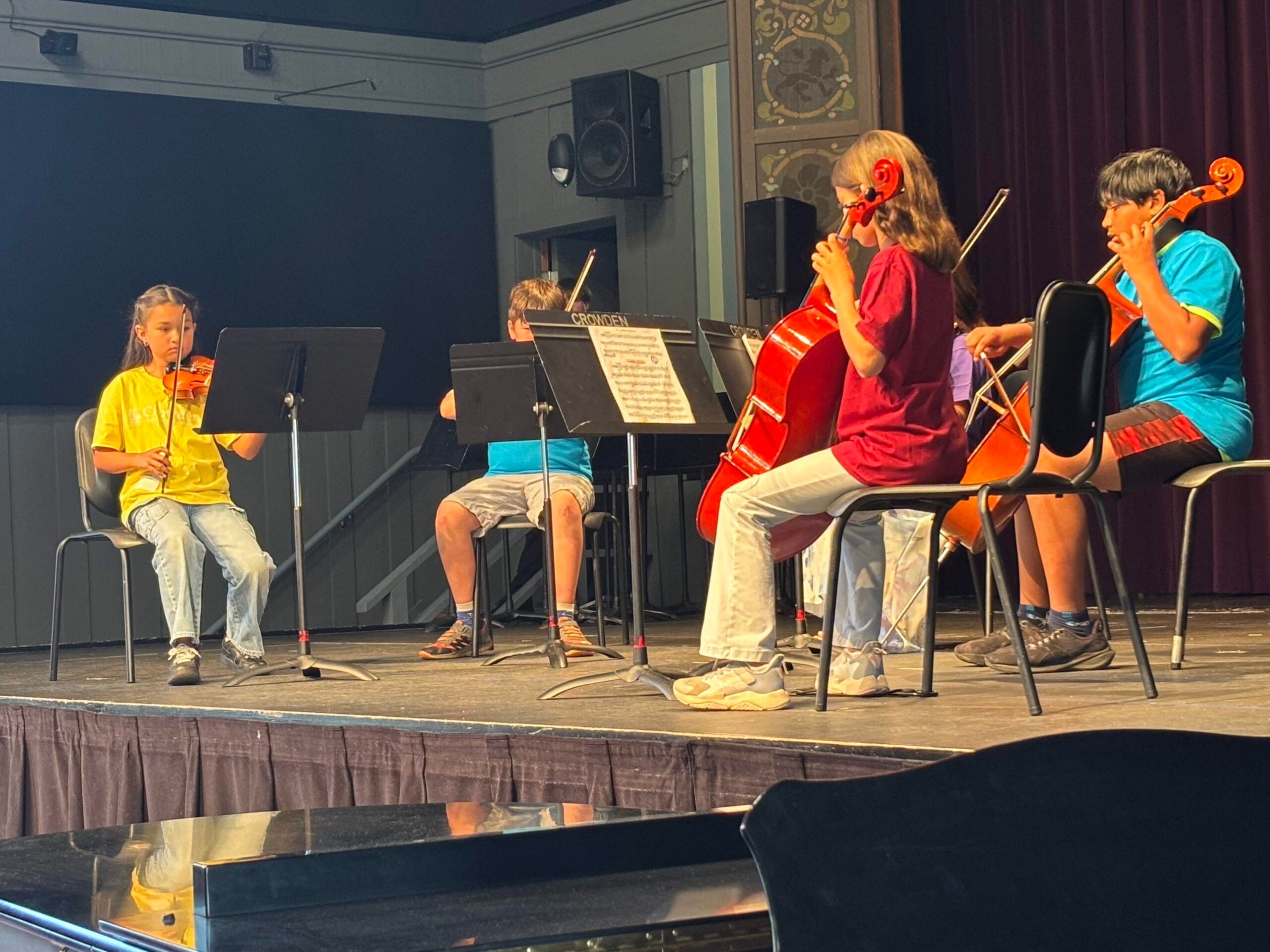 Crowden Students performing string instruments on stage recital