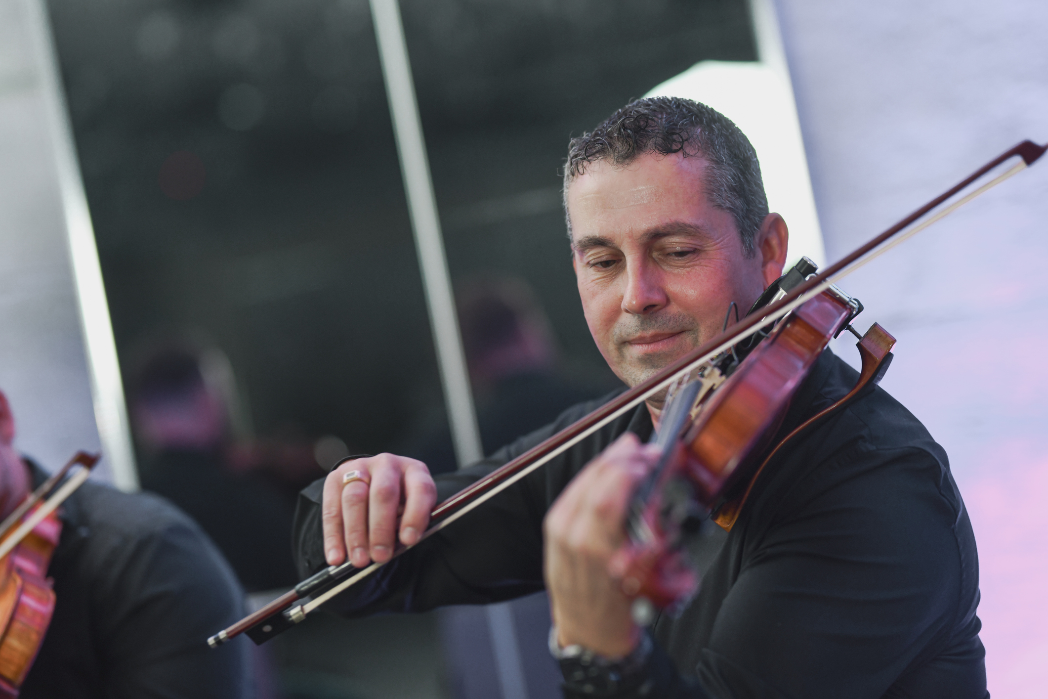 Man playing violin at event, focused on performance.