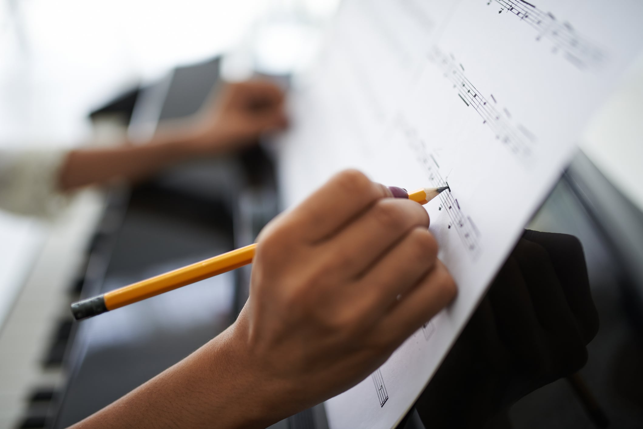 Hand writing on music sheet at piano.