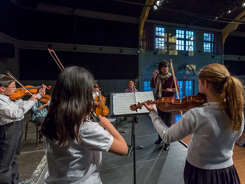 Students playing violin on stage