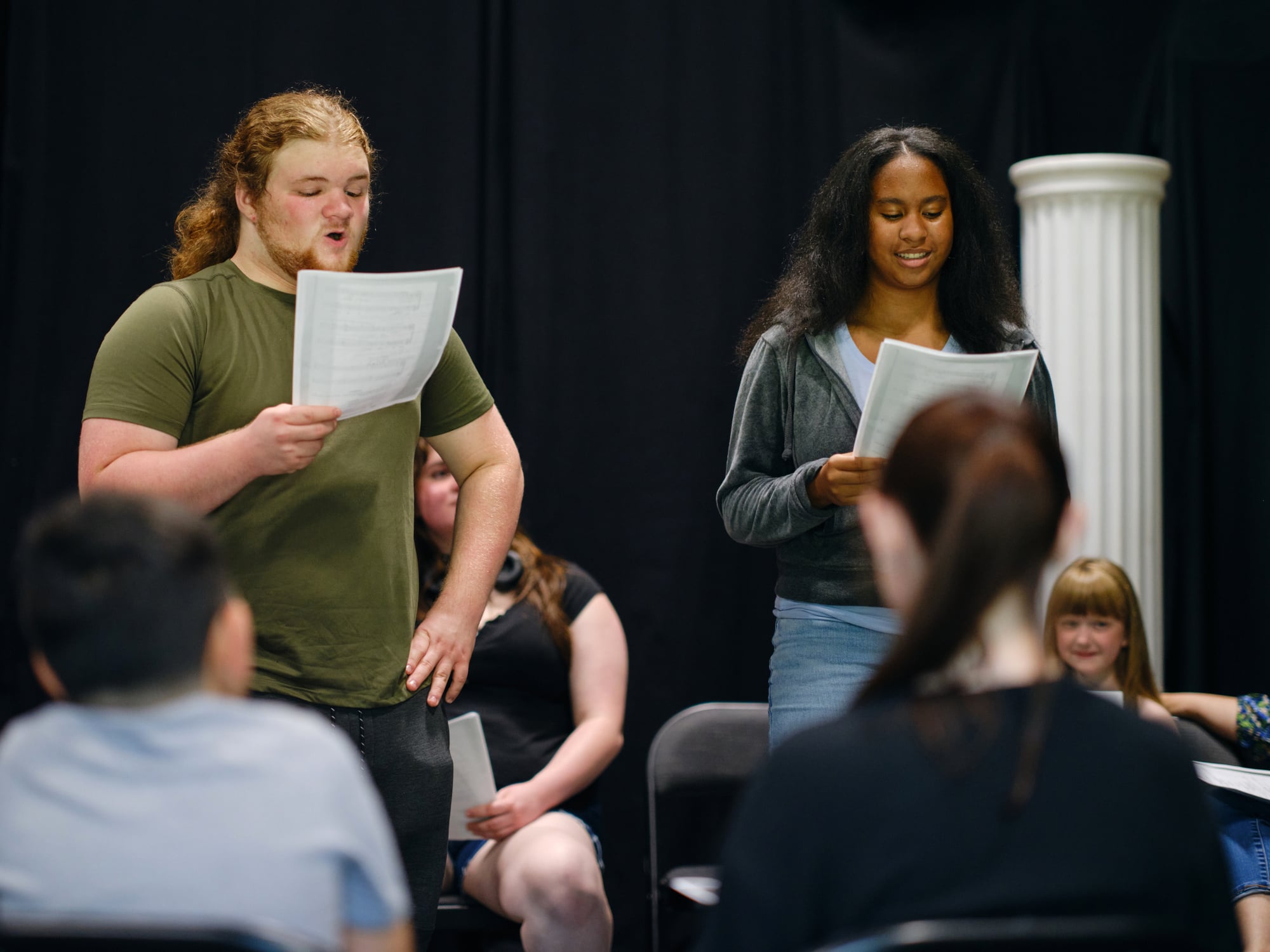 Actors reading scripts in rehearsal setting