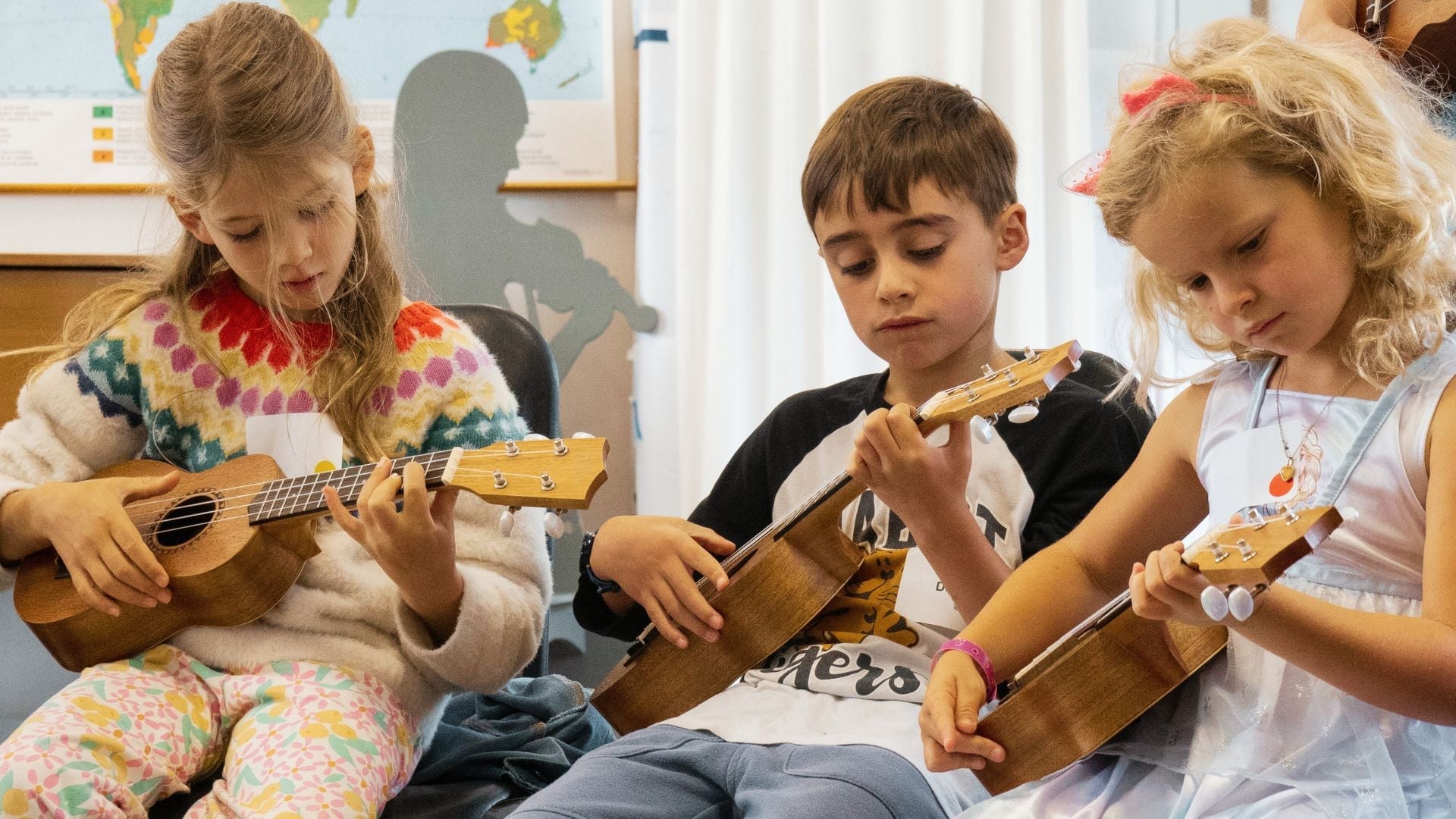 Children playing ukuleles in a classroom setting.