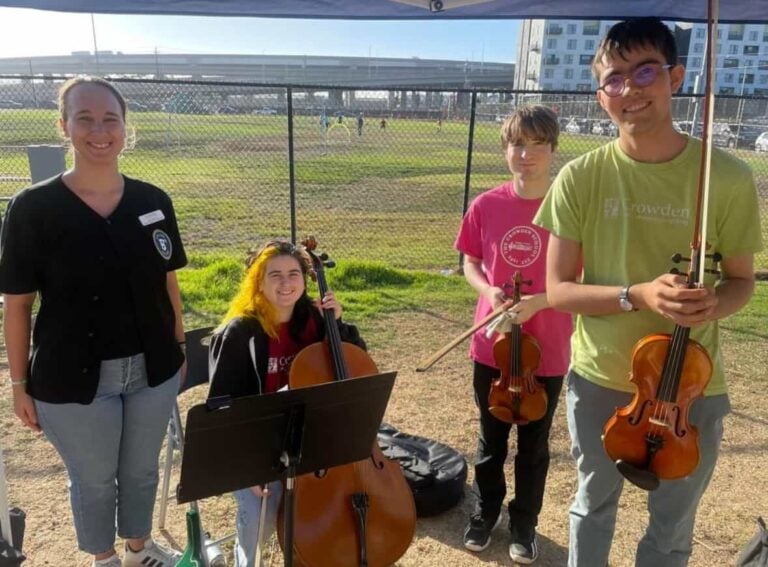 Group of musicians outdoors with string instruments.