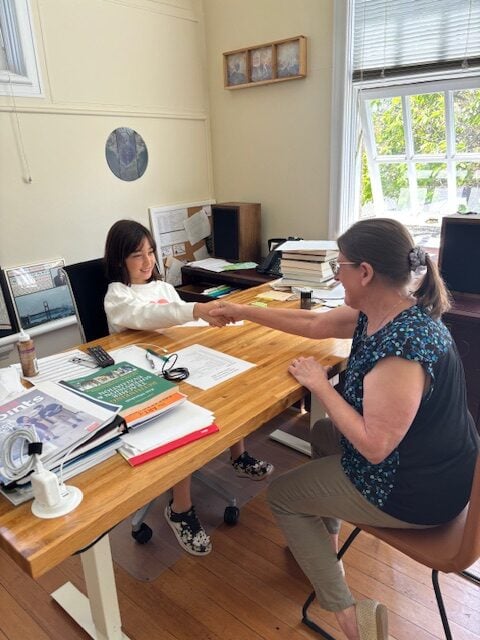 Two women discussing paperwork at a desk.