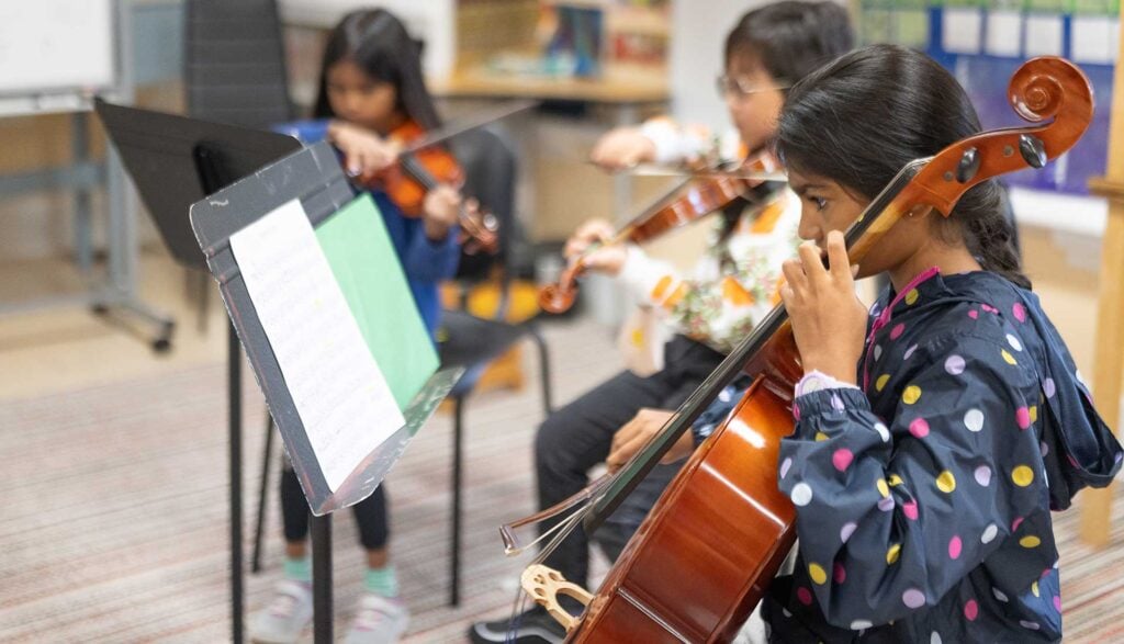 Children playing string instruments in music class.