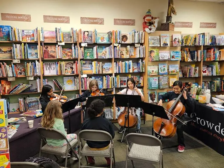 Children playing music in library setting.