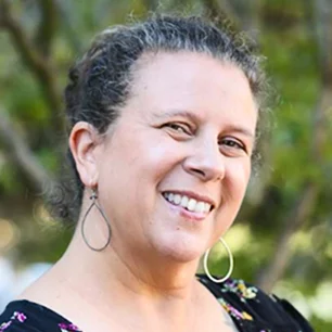 Smiling person outdoors with hoop earrings