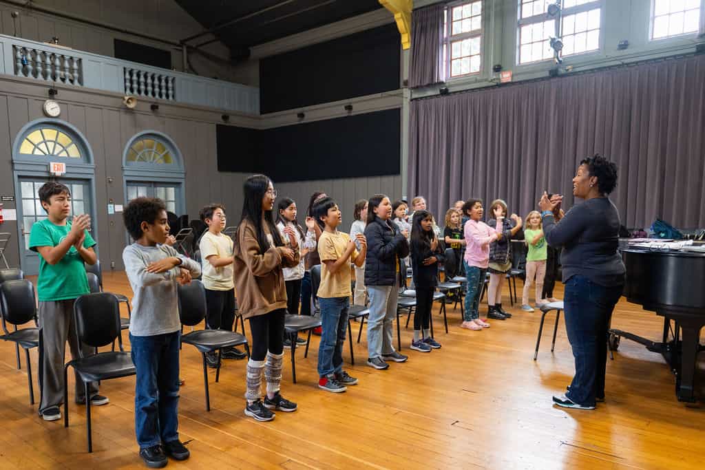 Children singing with teacher in music class.