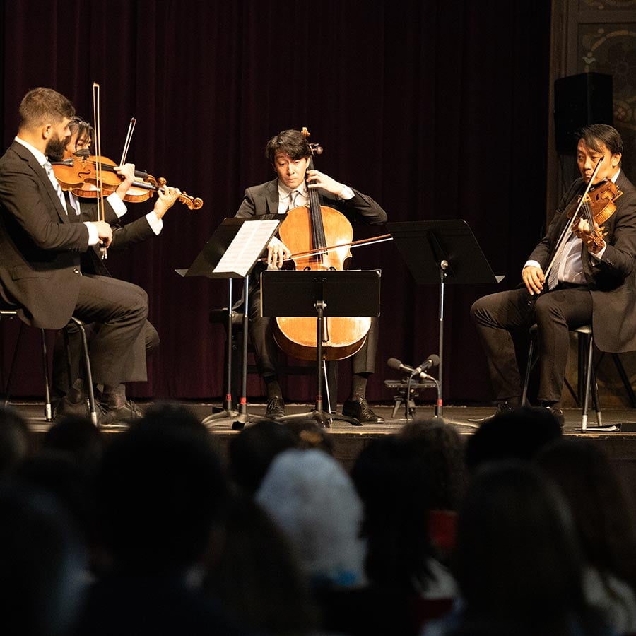 String quartet performing on stage for audience.