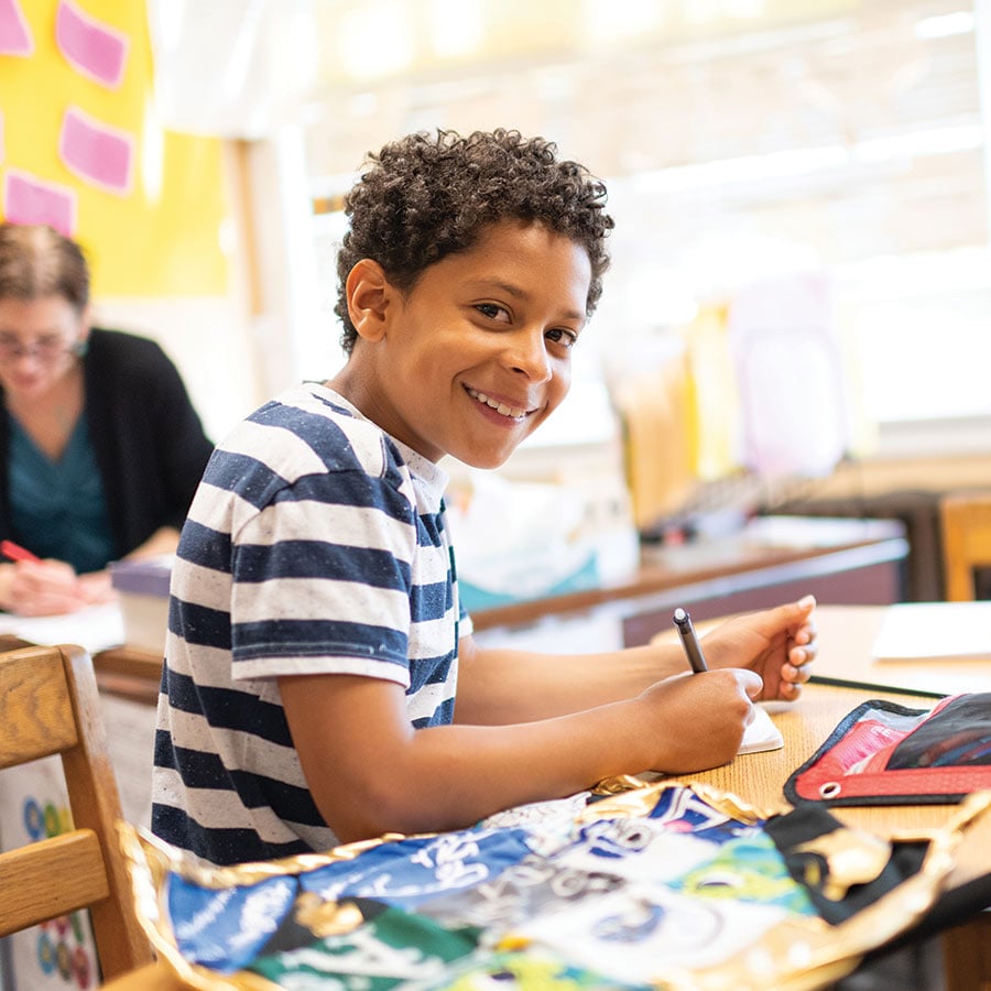 Smiling child writing at school desk