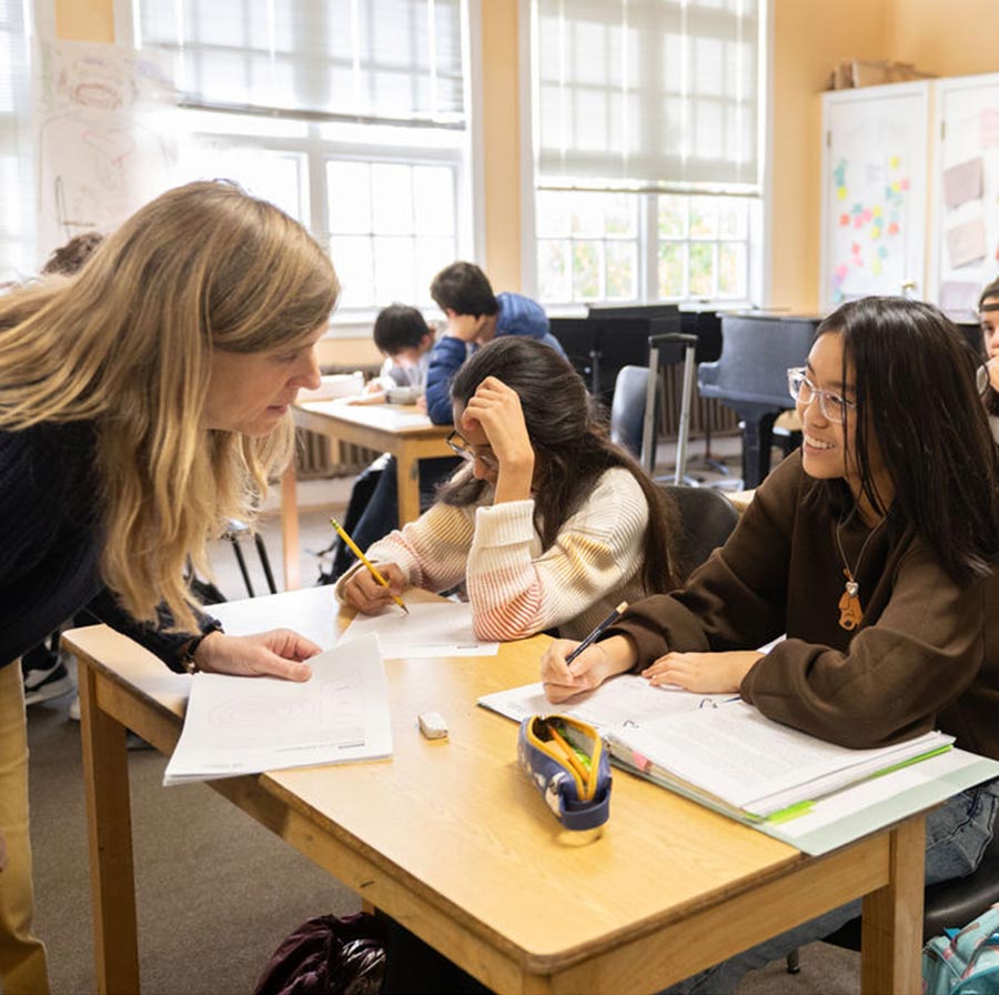Teacher helping students in classroom setting.