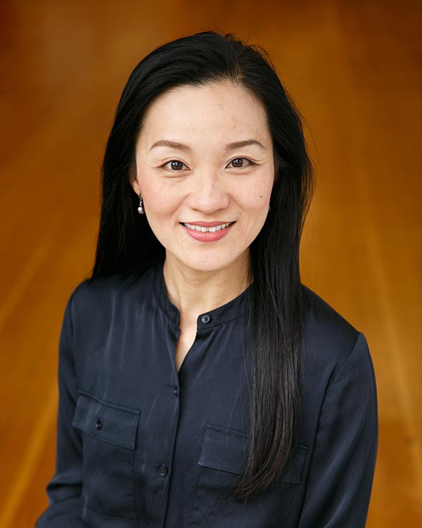 Smiling woman in black shirt on wooden floor.