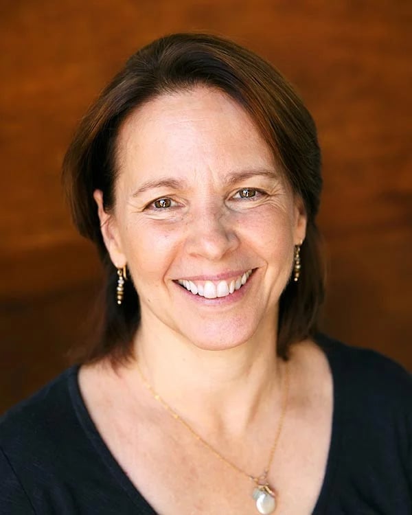 Smiling woman with brown hair and earrings.