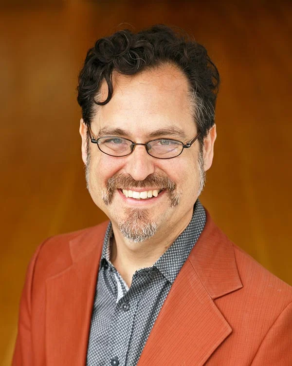 Man smiling in orange jacket and glasses