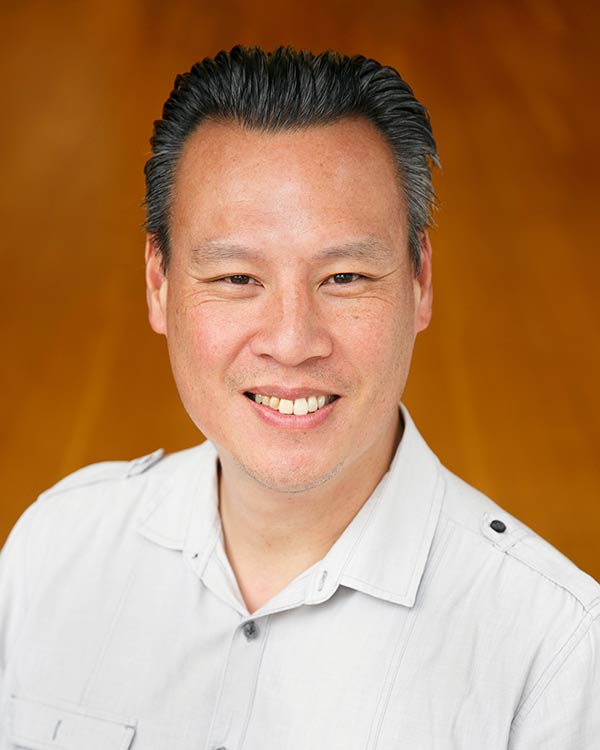 Smiling person in white shirt, orange background.