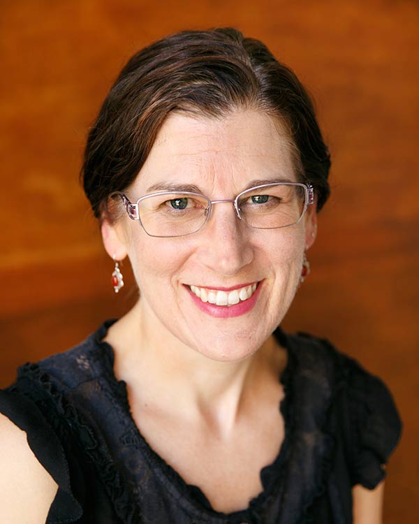 Smiling woman with glasses and earrings.