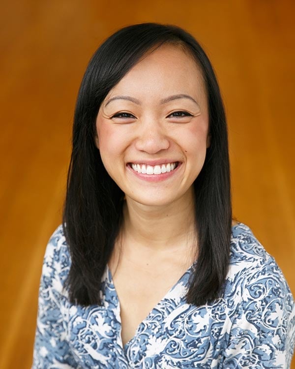 Smiling woman with long hair and patterned shirt.