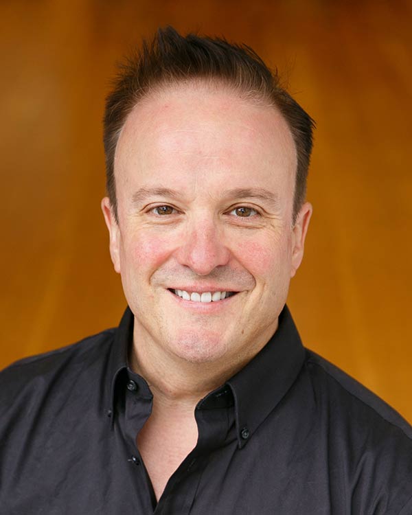 Smiling person with short hair, wearing black shirt.