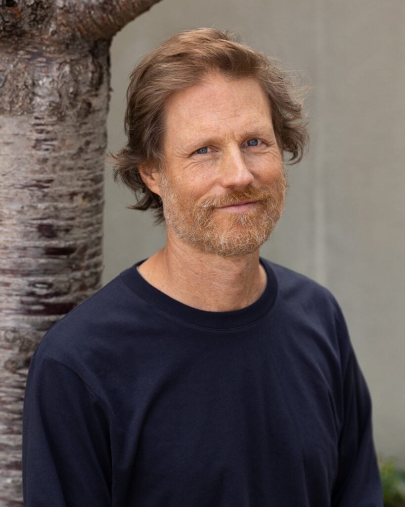 Man with beard and blue shirt near tree