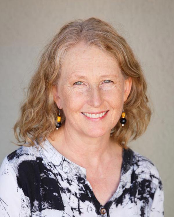 Smiling woman with curly hair and patterned shirt.