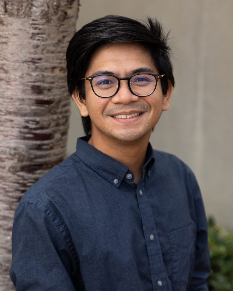 Smiling person wearing glasses and blue shirt.