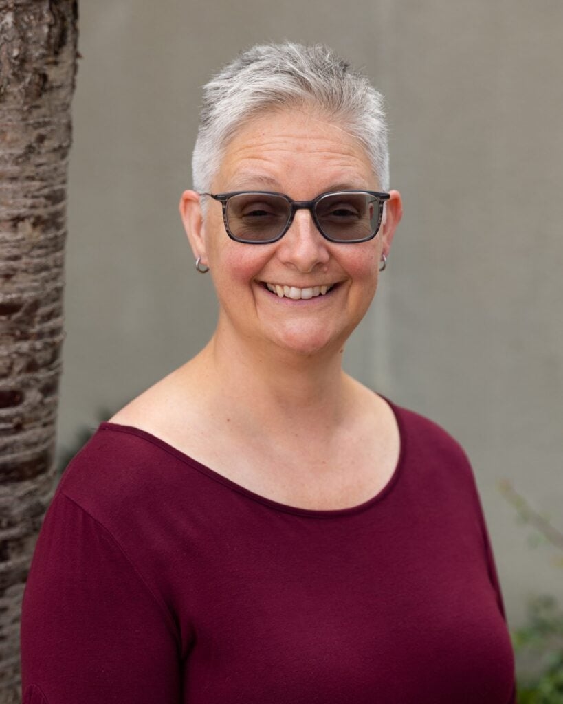 Smiling person with short hair wearing glasses