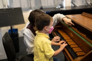 Child and teacher playing piano together