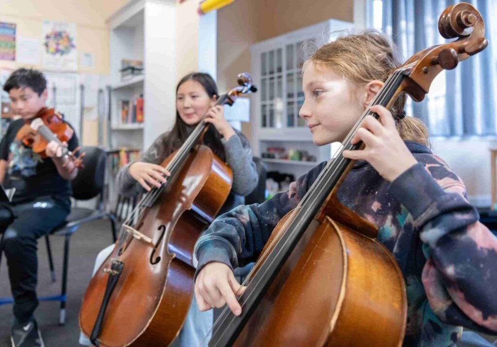 Students playing string instruments in music class.