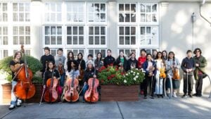 Group of musicians with string instruments outside a building.