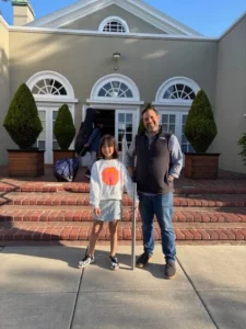 Child and adult smiling outside a building.