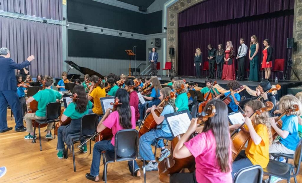 Orchestra concert with young musicians and conductor.