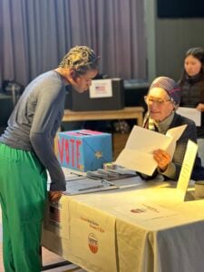 Voting station with people reviewing paperwork.