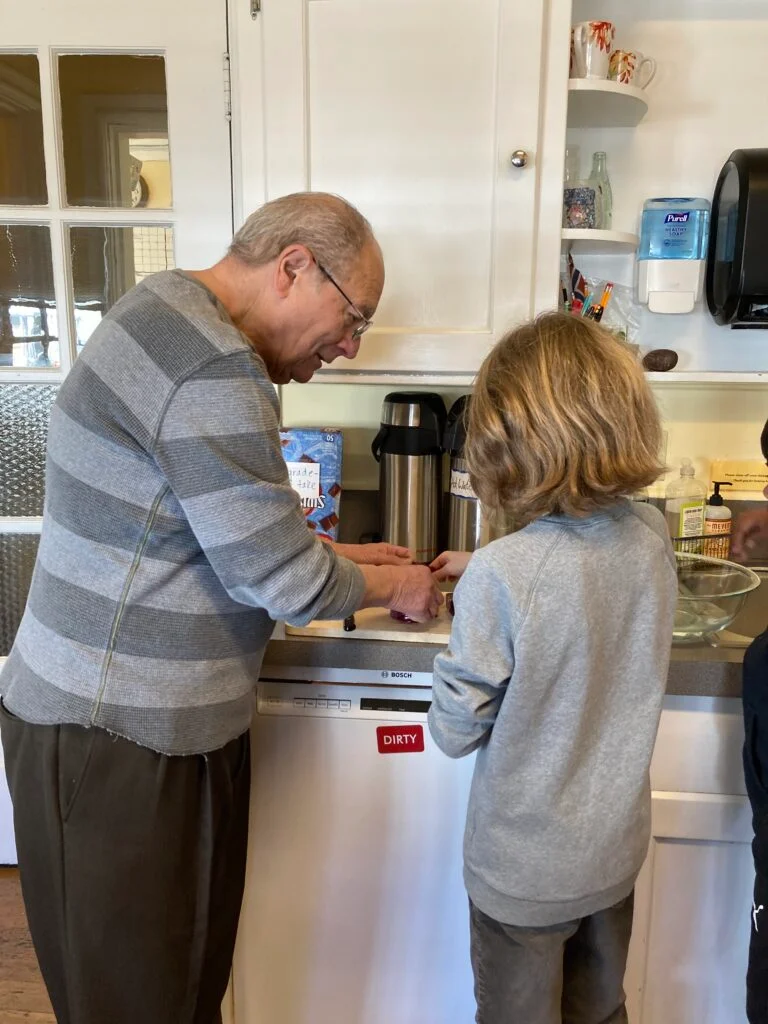 Elderly man and child working together in kitchen.