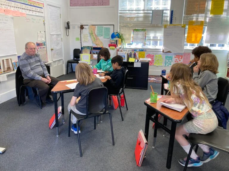 Teacher talking to students in classroom setting.