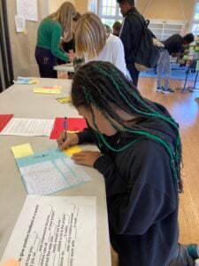 Students writing on paper at a table.