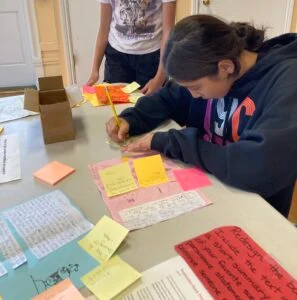 Person writing notes on colorful papers at table.