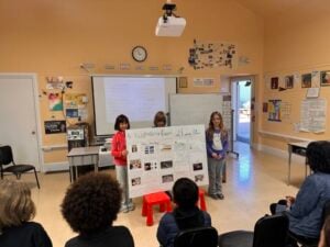 Children presenting project in classroom setting.