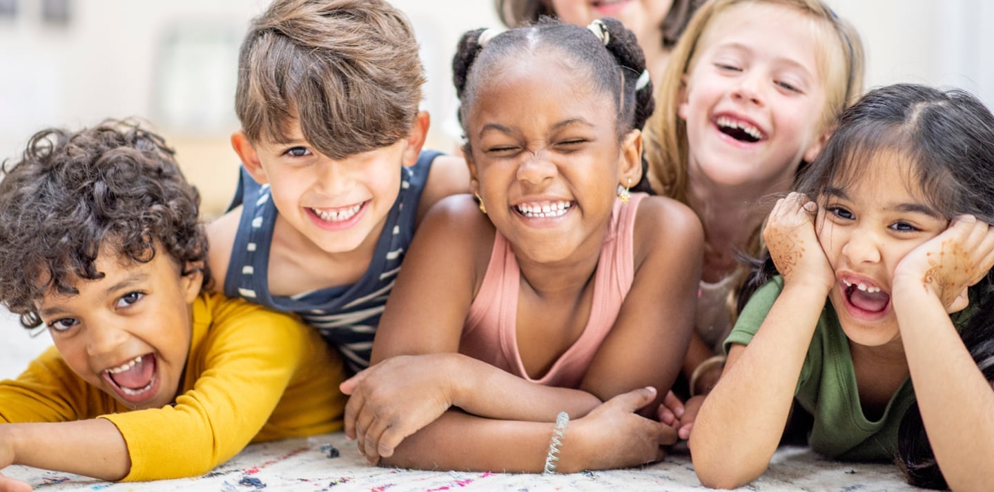 Happy children lying on carpet, smiling together.
