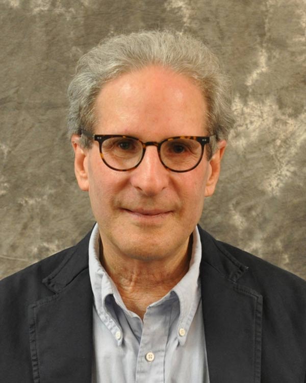 Man wearing glasses and suit, gray background.