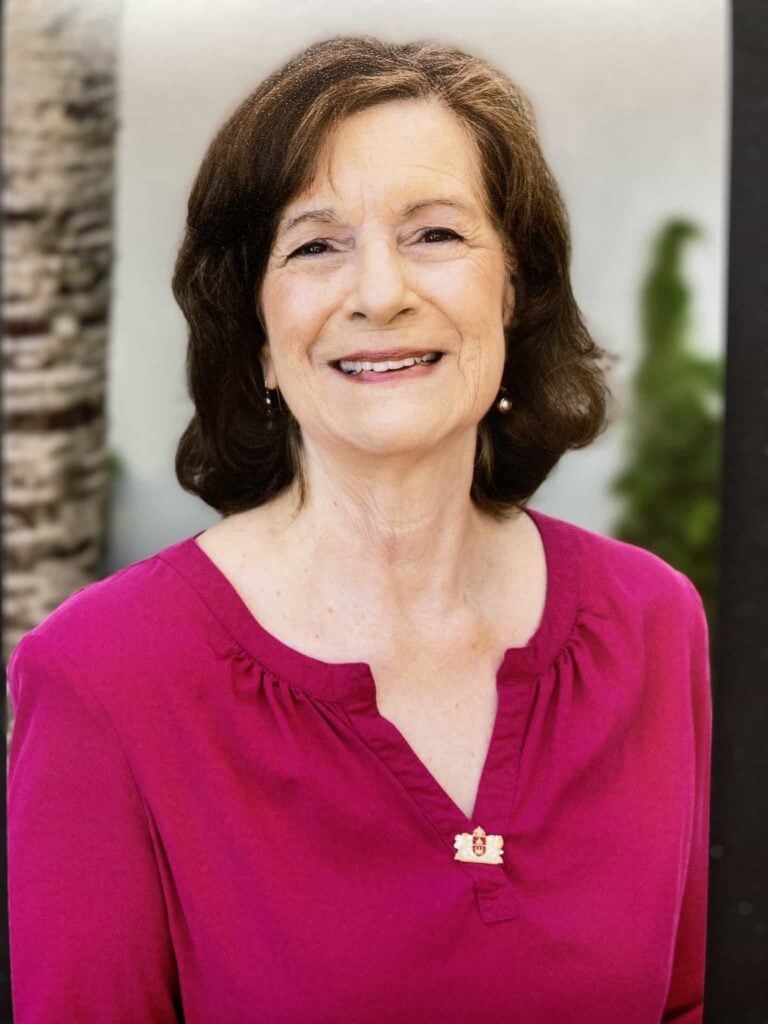 Smiling woman in pink top outdoors.
