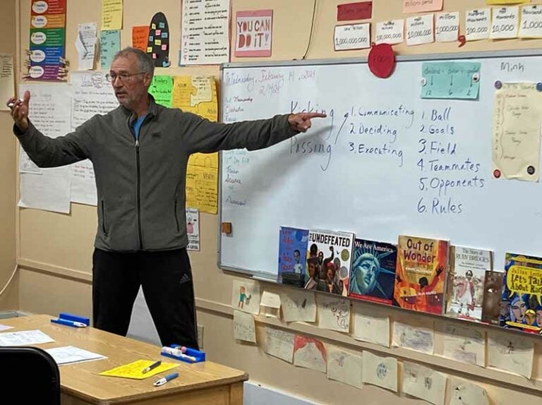 Man teaching in front of classroom whiteboard.