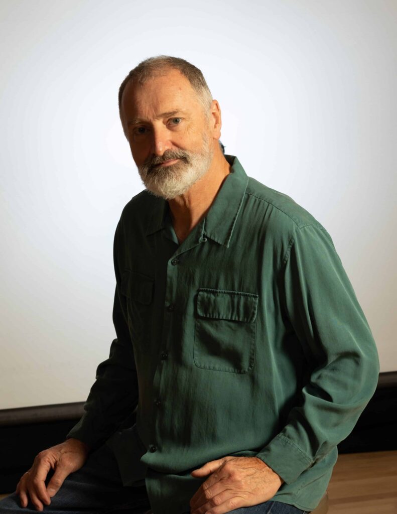 Man in green shirt sitting, thoughtful expression.