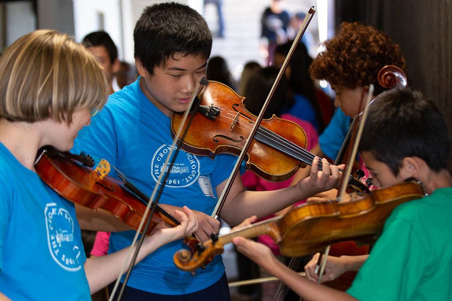 Children playing violins in a group rehearsal.