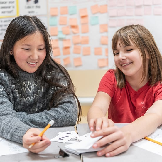 Two children smiling during classroom activity.