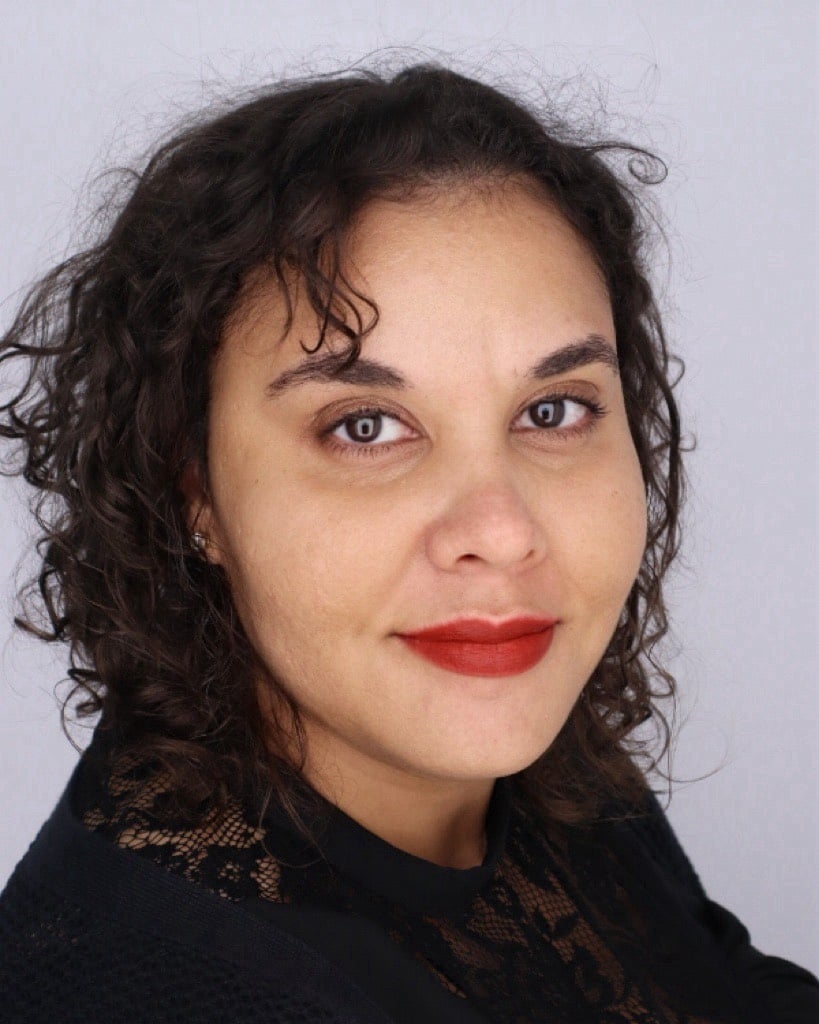 Woman with curly hair and red lipstick smiling.