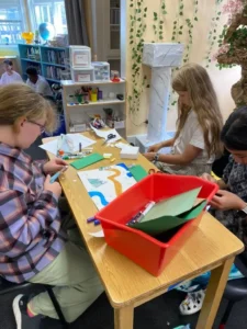 Students crafting at table in classroom.