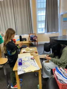 Children crafting with paper and scissors in classroom.
