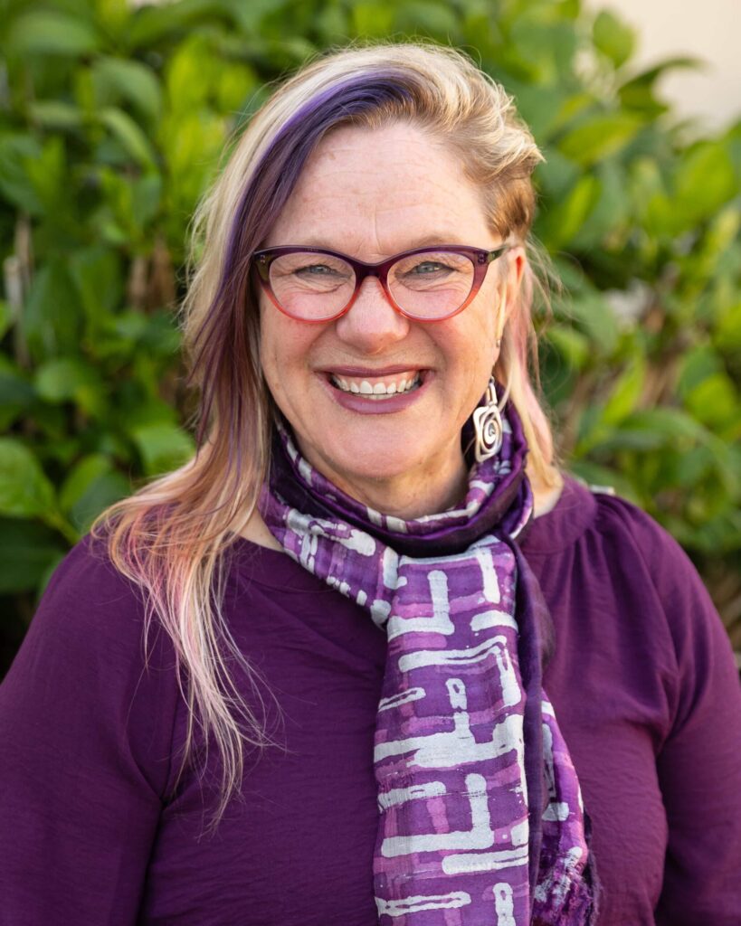Smiling person in purple outfit outdoors